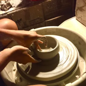 Beginner shaping clay on a pottery wheel during a class