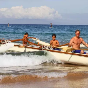 Group paddling Hawaiian outrigger canoes near coral reefs