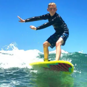 Child learning to surf with private instructor support