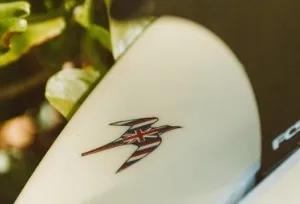 Short surfboard resting on sandy beach ready for rental