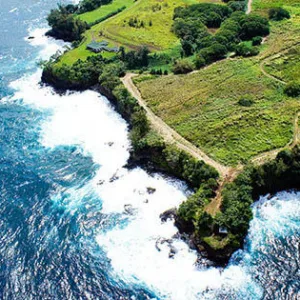 Boat cruising near Onomea Waterfall cliffs in Hawaii