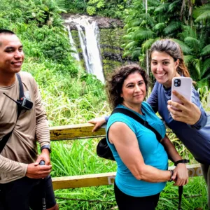 Hikers walking along a lush waterfall trail in a tropical forest