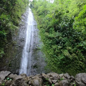 Hiker walking on trail toward tall waterfall