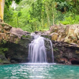 Hiker standing near tall waterfall in lush valley