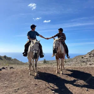 Couple horseback riding through lush mountain valley