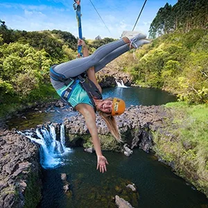 Zipliner soaring over waterfalls and lush forest