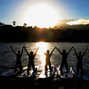 Paddleboarders gliding over coral reefs at sunrise