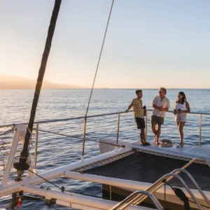 Catamaran sailing at sunset with passengers enjoying drinks