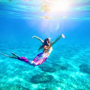 Person swimming underwater wearing colorful mermaid tail