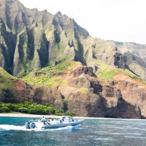 Rigid-hulled inflatable boat cruising along Nāpali Coast cliffs